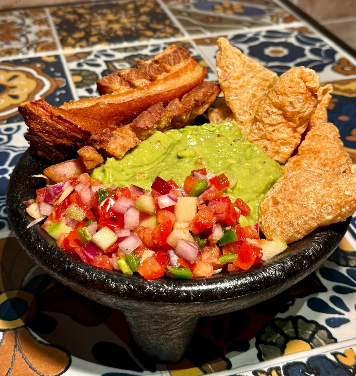 Guacamole Cantina with pico de gallo, chicharrón and crispy toppings in a stone bowl at Jalapeños